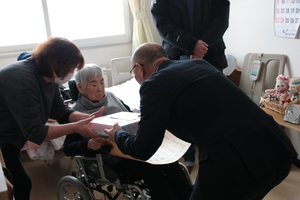 佐々木ヨシヱさんに100歳のお祝いをお渡ししている様子